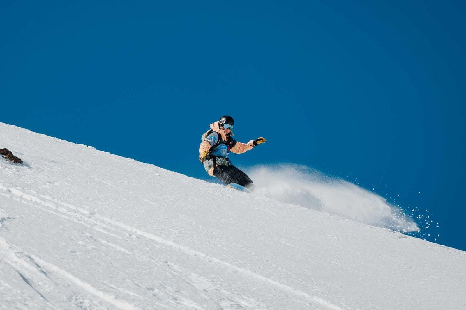 Snowboardista na svahu pod modrou oblohou